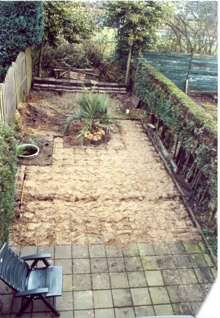 Hier is de tuin te zien, waarbij er vele stoeptegels zijn weggehaald en gebruikt zijn om een bult te maken achter in de tuin